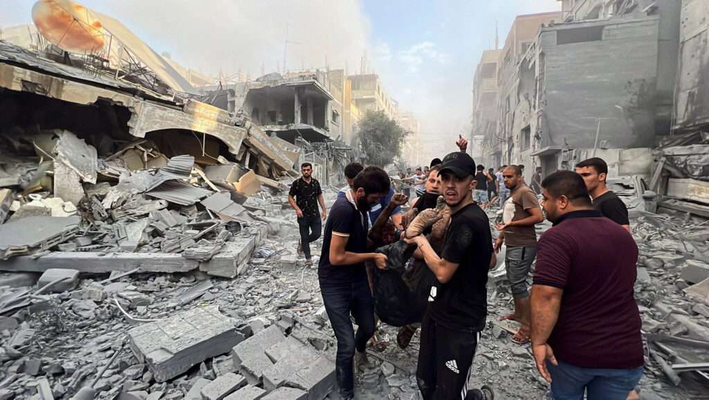 Palestinians carry a casualty at the site of Israeli strikes on houses, in Gaza City